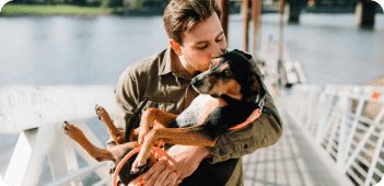 man holding his emotional support dog by a lake