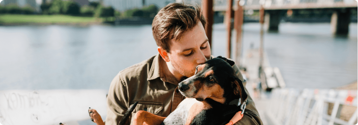 man holding his emotional support dog by a lake